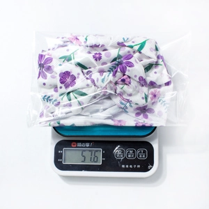 Vue détaillée du bandeau bébé à fleurs pesant 57,6 g dans son emballage transparent