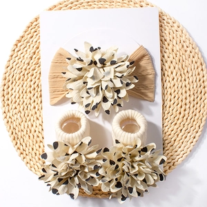 Close-up of floral jacquard baby headband and matching socks on a woven mat