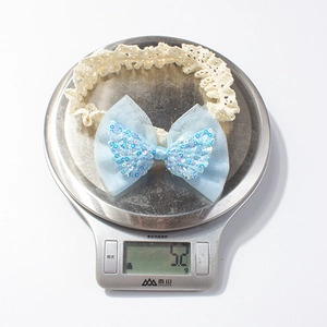 Dettaglio della fascia per neonati in pizzo da 5,2g con fiocco blu e paillettes