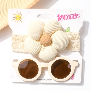 Detail von Baby-Spitzenstirnband mit Kordblume und beige Retro-Rundsonnenbrille