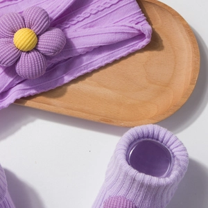 Detailed macro view of purple knitted baby headband with flower and ribbed cotton socks
