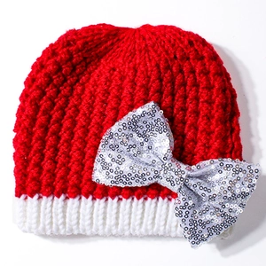 Detail of red and white knitted baby beanie featuring a large silver sequin bow decoration