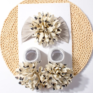 Detail of baby headband and socks set with large beige fabric flowers and black hearts