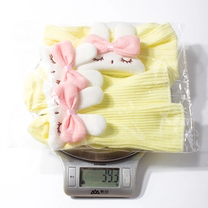 Detail view of yellow knit baby socks with bunny ears on scale weighing 39.3g