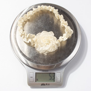 Détail d'un bandeau en dentelle pour bébé de 5,3g avec fleur en satin et perles centrales