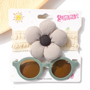 Spitzen-Baby-Haarband mit Cord-Blume und runder Sonnenbrille auf Sommerkarte
