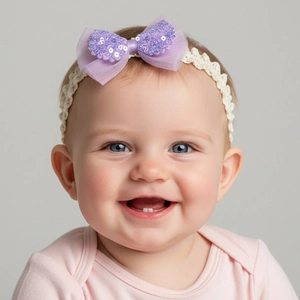 Detail eines Baby-Haarbandes mit lila Pailletten-Schleife und cremefarbenem Spitzenband