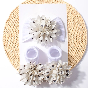 Detail of white baby headband and socks set with black polka dot 3D floral accents