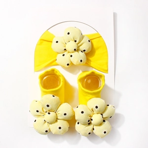 Detail von gelbem Baby-Stirnband und Socken-Set mit 3D-Blumen auf weißer Karte