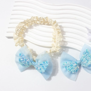 Dettaglio della fascia in pizzo per neonati con fiocco in tulle blu e paillettes cangianti