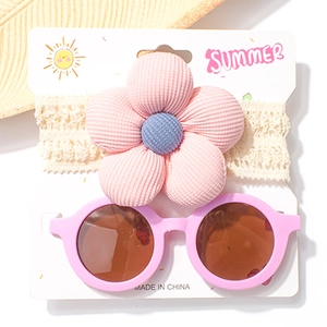 Detailset aus rosa Cord-Blumen-Stirnband und runder Sonnenbrille auf einer Displaykarte