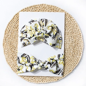 Bonnet et bandeau pour bébé à fleurs sur carte blanche avec détail de tapis tissé