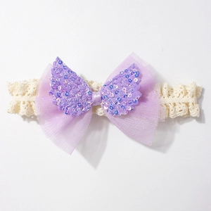 Dettaglio fascia neonata in pizzo con fiocco viola a doppio strato e ali di paillettes