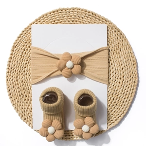 Detailed view of baby headband and socks set with 3D floral knit textures in warm brown