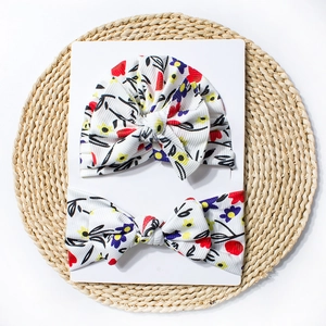 Détail d'un bonnet à nœud pour bébé et bandeau floral assorti en maille côtelée blanche