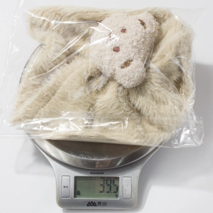 Close-up of beige plush bear hat on electronic scale weighing 39.5 grams