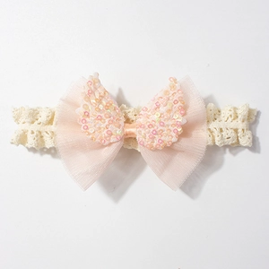Dettaglio della fascia per neonata in pizzo con fiocco in rete rosa e ali di paillettes
