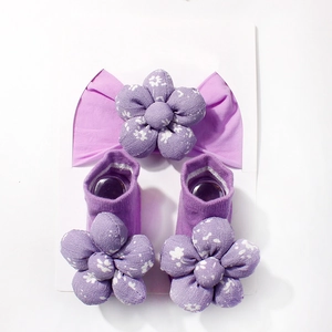 Detailansicht von lila Baby-Stirnband und Socken-Set mit 3D-Blumen auf Display-Karte