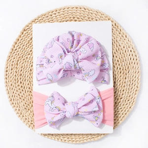Détail d'un bonnet turban bébé à motif licorne rose et d'un ensemble bandeau assorti