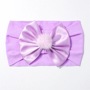 Détail d'un bandeau lilas pour bébé avec grand nœud en satin et pompon rose doux