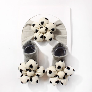 Detailansicht von grauem Baby Stirnband und Socken Set mit cremefarbenen 3D Blumen Mustern