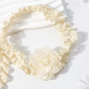 Détail du bandeau en dentelle pour bébé avec fleur en organza et perles sur plateau