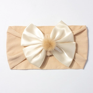 Détail du bandeau en nylon pour bébé avec grand nœud en satin et pompon marron