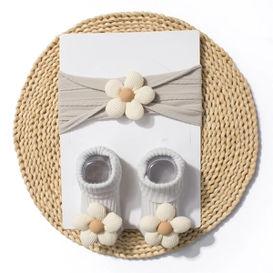 Close-up of light grey knit baby headband and socks set with cream floral accents
