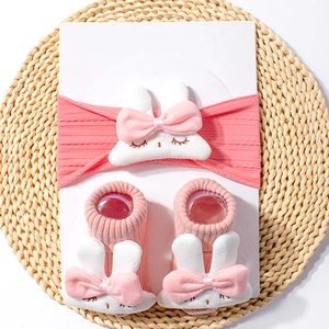 Detailed view of pink ribbed baby headband and socks set with plush bunny decor