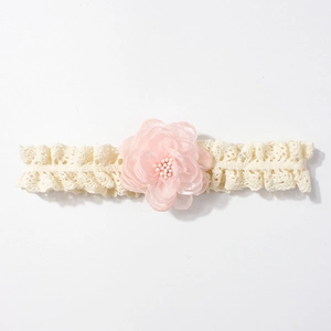 Détail d'un bandeau en dentelle pour bébé avec fleur en mousseline rose et perle