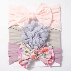 Three-piece baby headband set featuring bows and flowers on a white display card