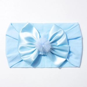 Détail du bandeau bébé bleu clair en nylon avec un nœud en satin et pompon en peluche