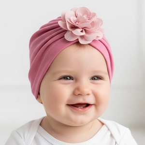 Dettaglio di un neonato con un turbante in maglia rosa scuro decorato con un grande fiore