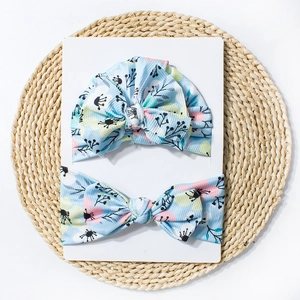 Détail de l'ensemble bonnet turban bébé fleuri bleu clair et bandeau à nœud sur carton