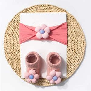 Detail of pink ribbed baby headband and socks set featuring soft fabric flower ornaments