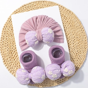 Vue détaillée d'un ensemble turban et chaussettes bébé violet avec nœud brodé sur paille