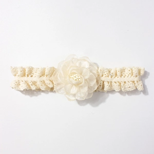 Gros plan d'un bandeau en dentelle pour bébé avec fleur en mousseline et perles