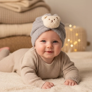 Close-up of soft grey plush baby hat with a cute cream bear patch for winter warmth