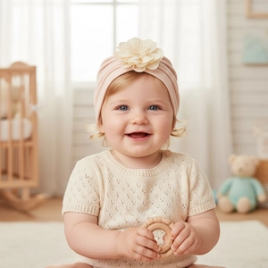 Dettaglio del cappello a turbante rosa per neonata con grande fiore decorativo crema