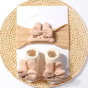 Detail view of baby knit headband and socks set with plush rabbit and bow decorations