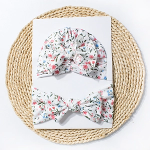 Détail d'un ensemble turban et bandeau fleuris pour bébé en maille côtelée avec nœuds