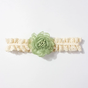 Gros plan détaillé d'un bandeau en dentelle pour bébé avec une fleur en tissu vert doux