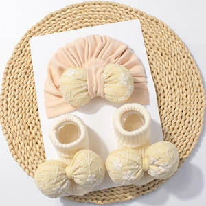 Ensemble bonnet et chaussettes bébé rose avec nœuds floraux sur tapis de paille