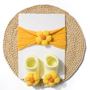 Detail of baby headband and socks set featuring 3D knit flowers on orange fabric