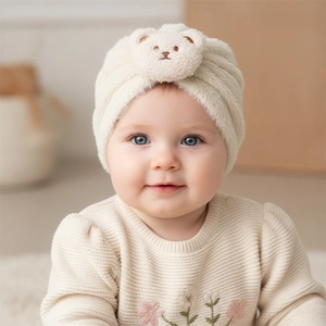 Detailed view of plush beige baby turban hat with a cute brown bear embroidery