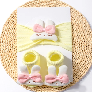 Close-up of yellow baby headband and socks set featuring soft plush 3D bunny details