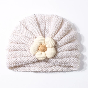 Dettaglio del cappello in maglia color crema per neonati con fiore 3D e trama a coste