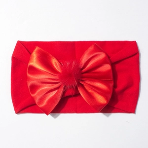 Détail du bandeau bébé en nylon rouge avec nœud en satin et pompon moelleux pour nourrissons