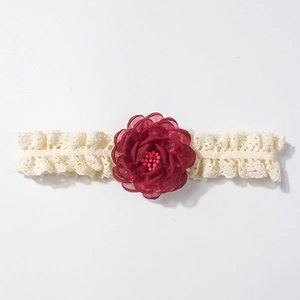 Détail d'un bandeau bébé en dentelle crème avec fleur en mousseline bordeaux et perles