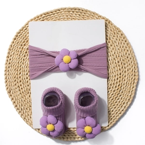 Detailed macro view of lilac baby headband and socks set with 3D knitted flower accents